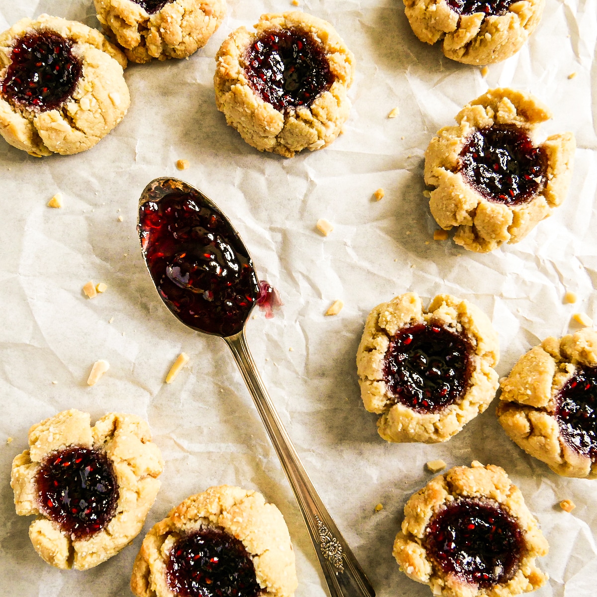 chewy thumbprint cookies with almond flour arranged on parchment paper.