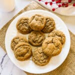 plate of chewy ginger snap cookies with red holly in the background.