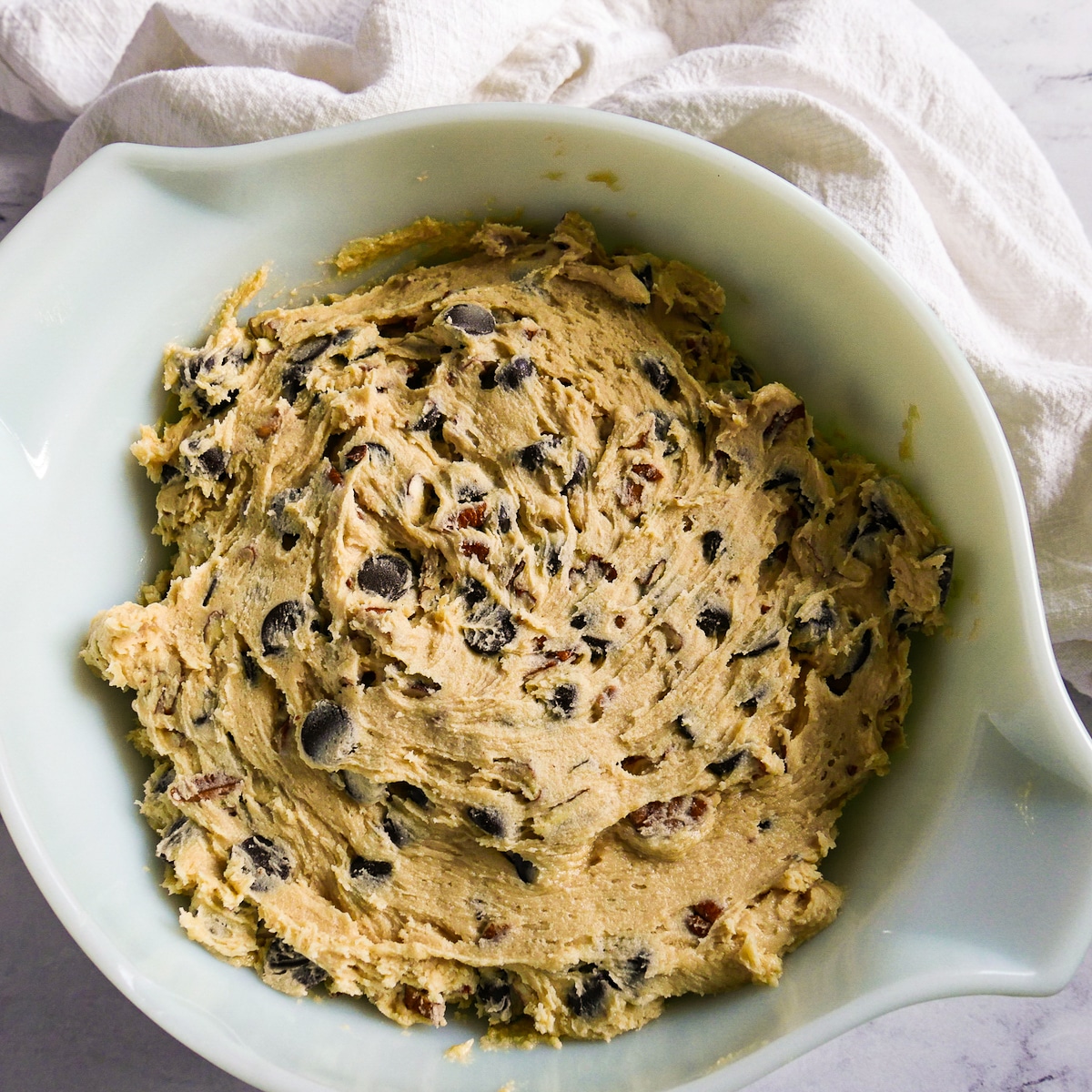 chocolate-chips-and-pecans-in-cookie-dough.jpg chocolate chips and pecans mixed into cookie dough.