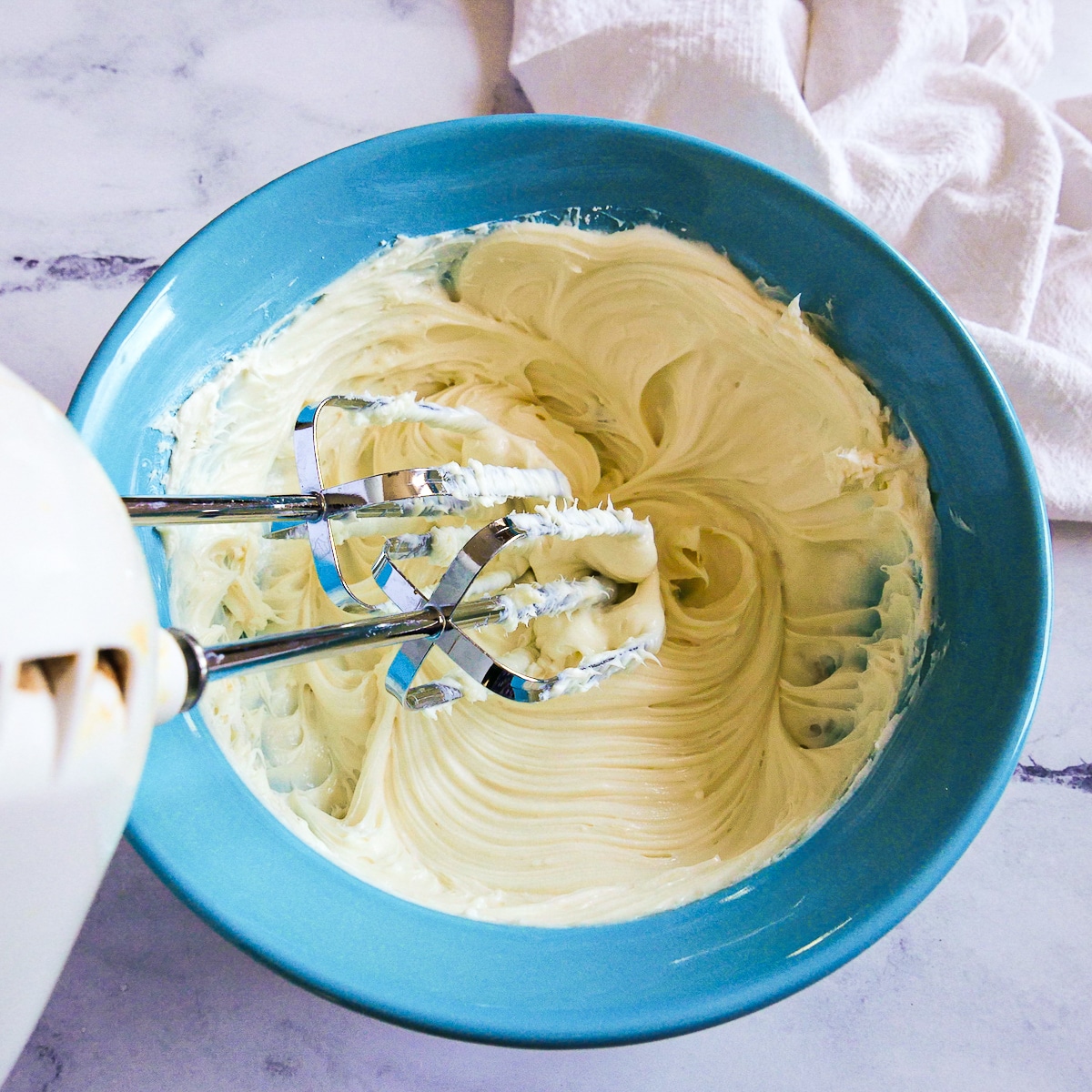 cream cheese, powdered sugar, and vanilla extract being mixed together.