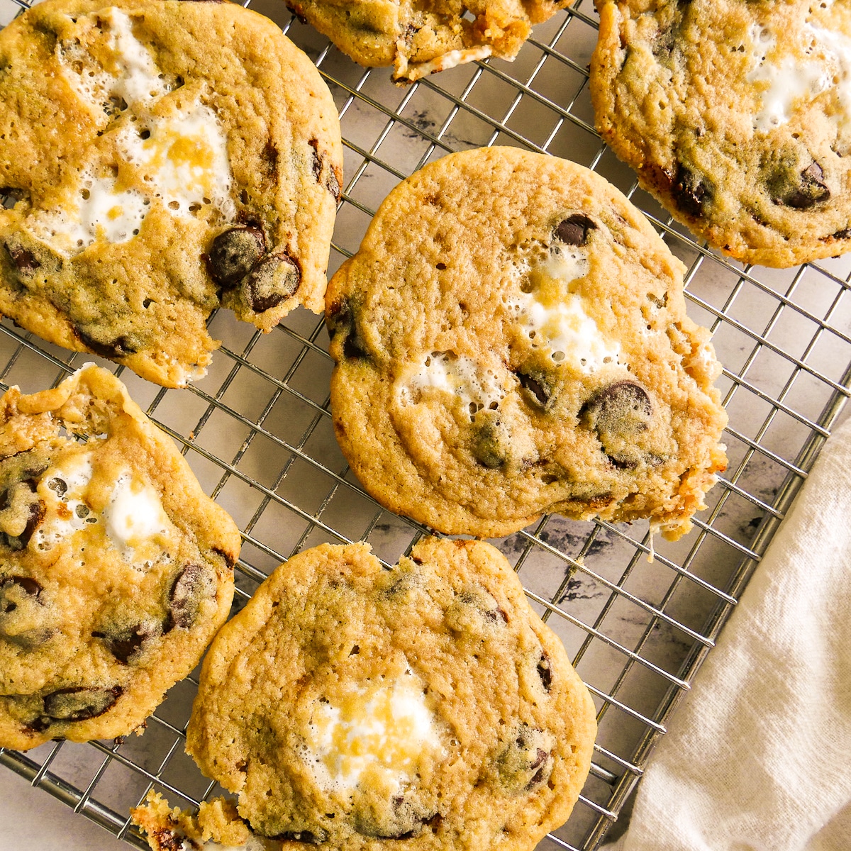 Baked chewy cookies with marshmallows on a cooling rack.