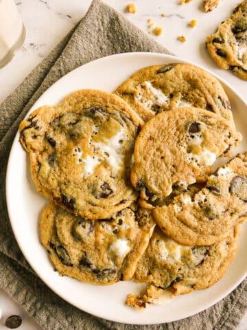 Gooey marshmallow chocolate chip cookies arranged on a white plate.