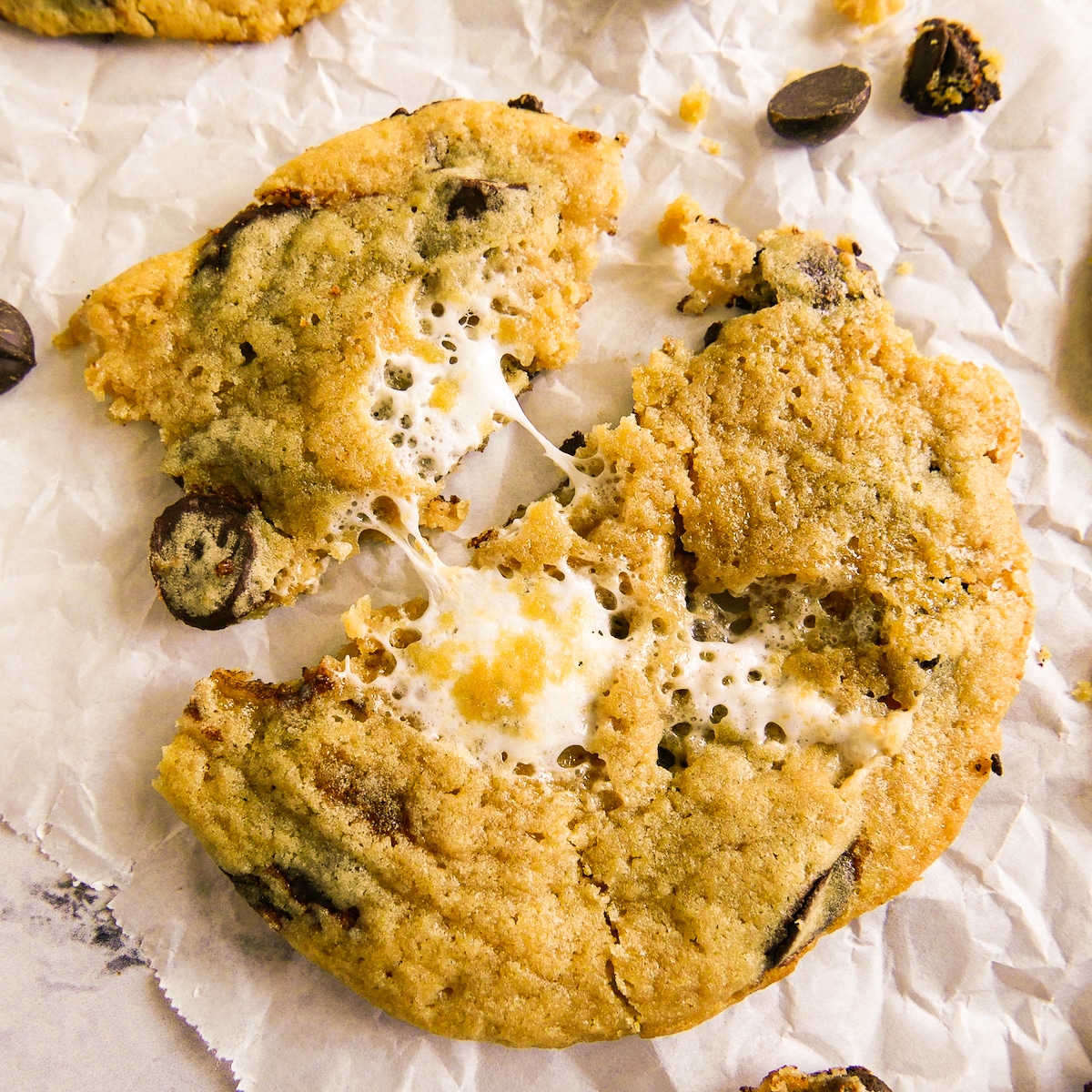 Pulled apart gooey marshmallow cookie on a piece of parchment.