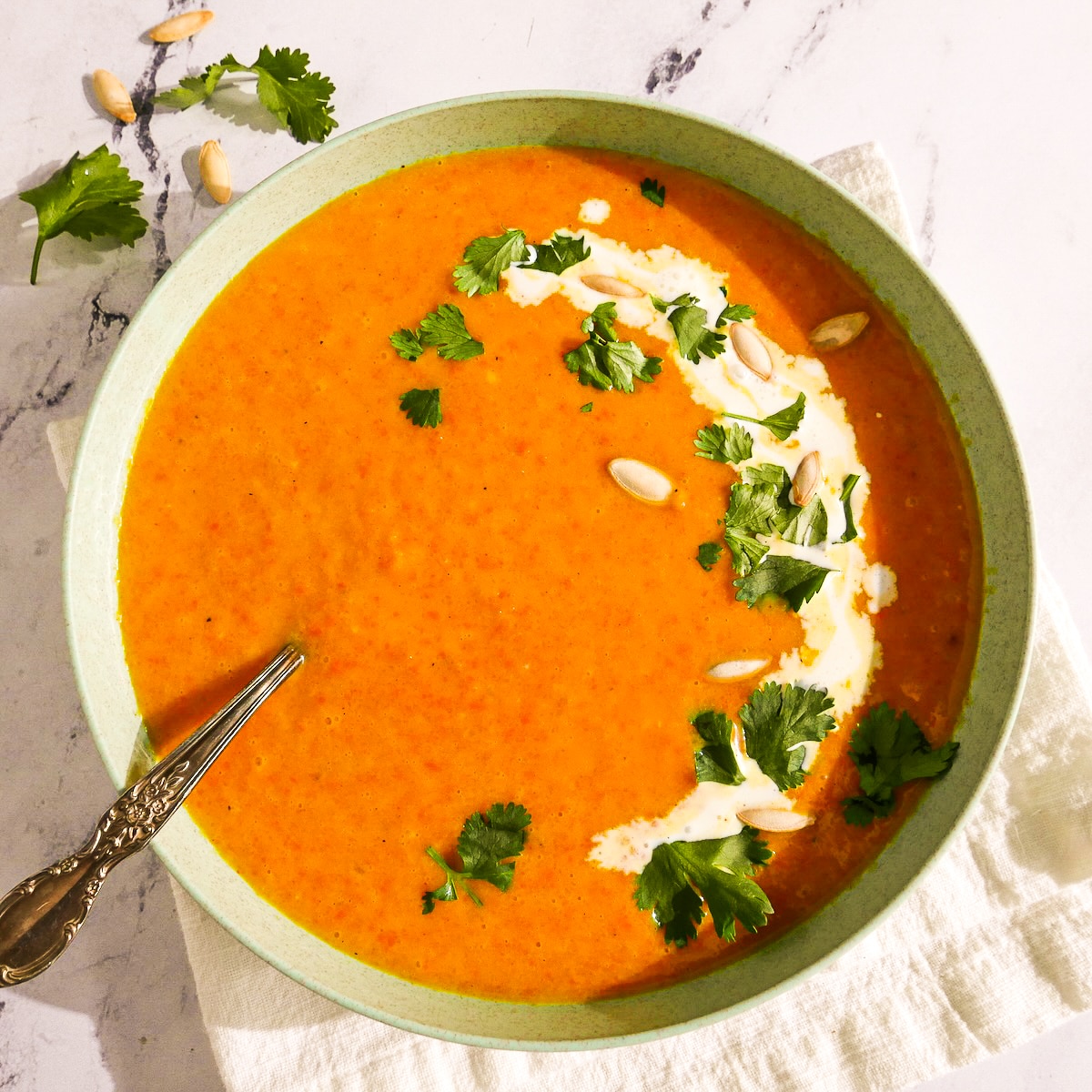 Creamy vegan soup garnished with cilantro and pumpkin seeds. 