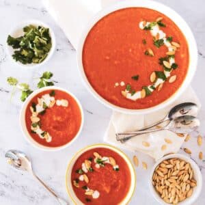 Creamy squash carrot ginger soup distributed in 3 bowls.