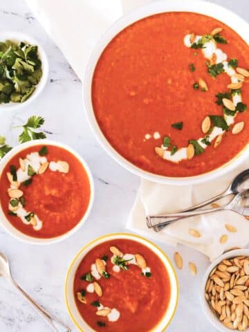 Creamy squash carrot ginger soup distributed in 3 bowls.