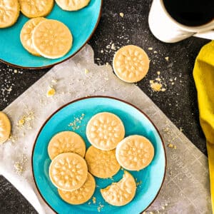 Aromatic cardamom shortbread cookies arranged on two blue plates with a cup of coffee.