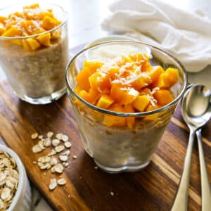 Creamy mango overnight oats arranged in two glass cups.