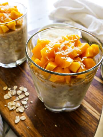 Creamy mango overnight oats arranged in two glass cups.