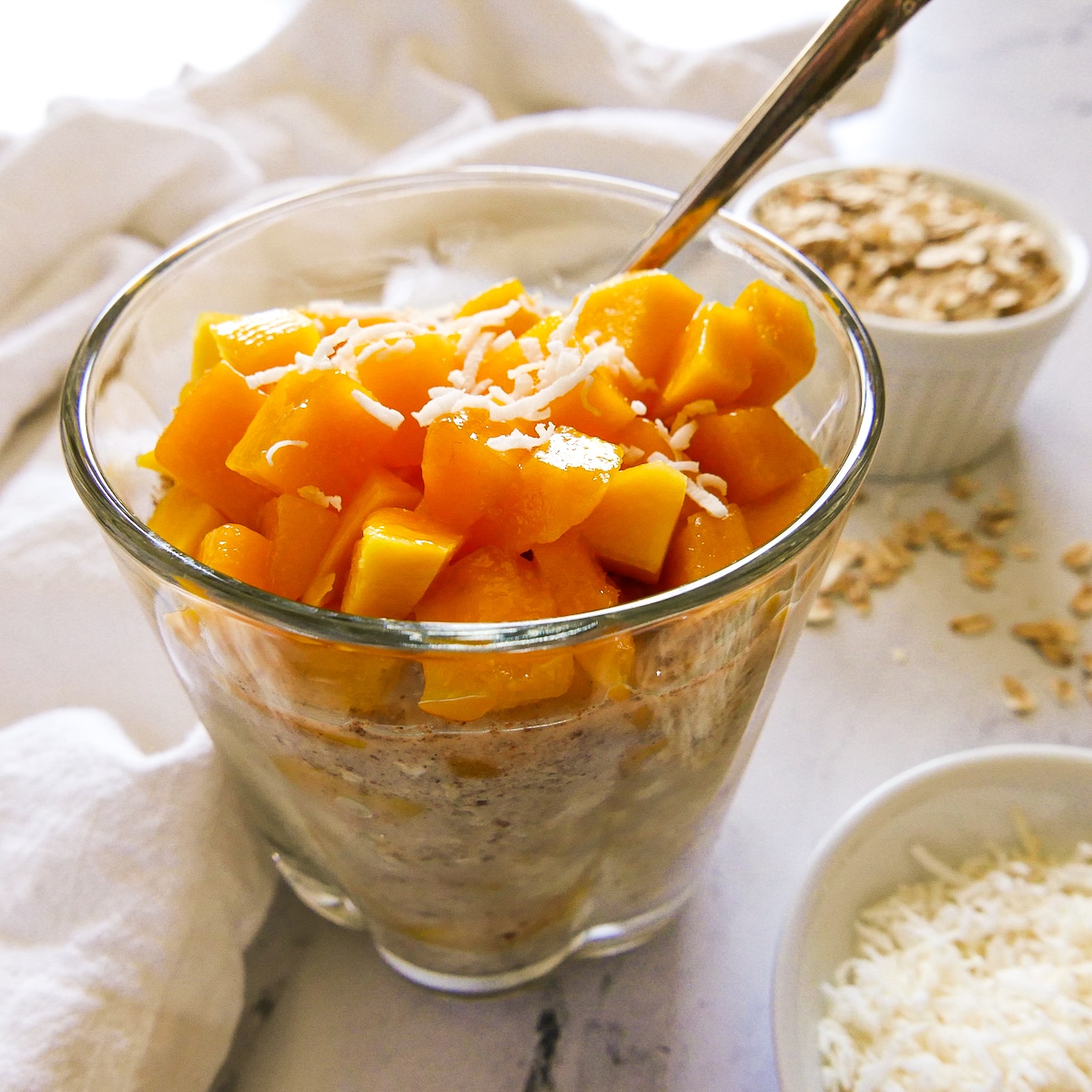 Vegan overnight oats arranged in a glass with a spoon.