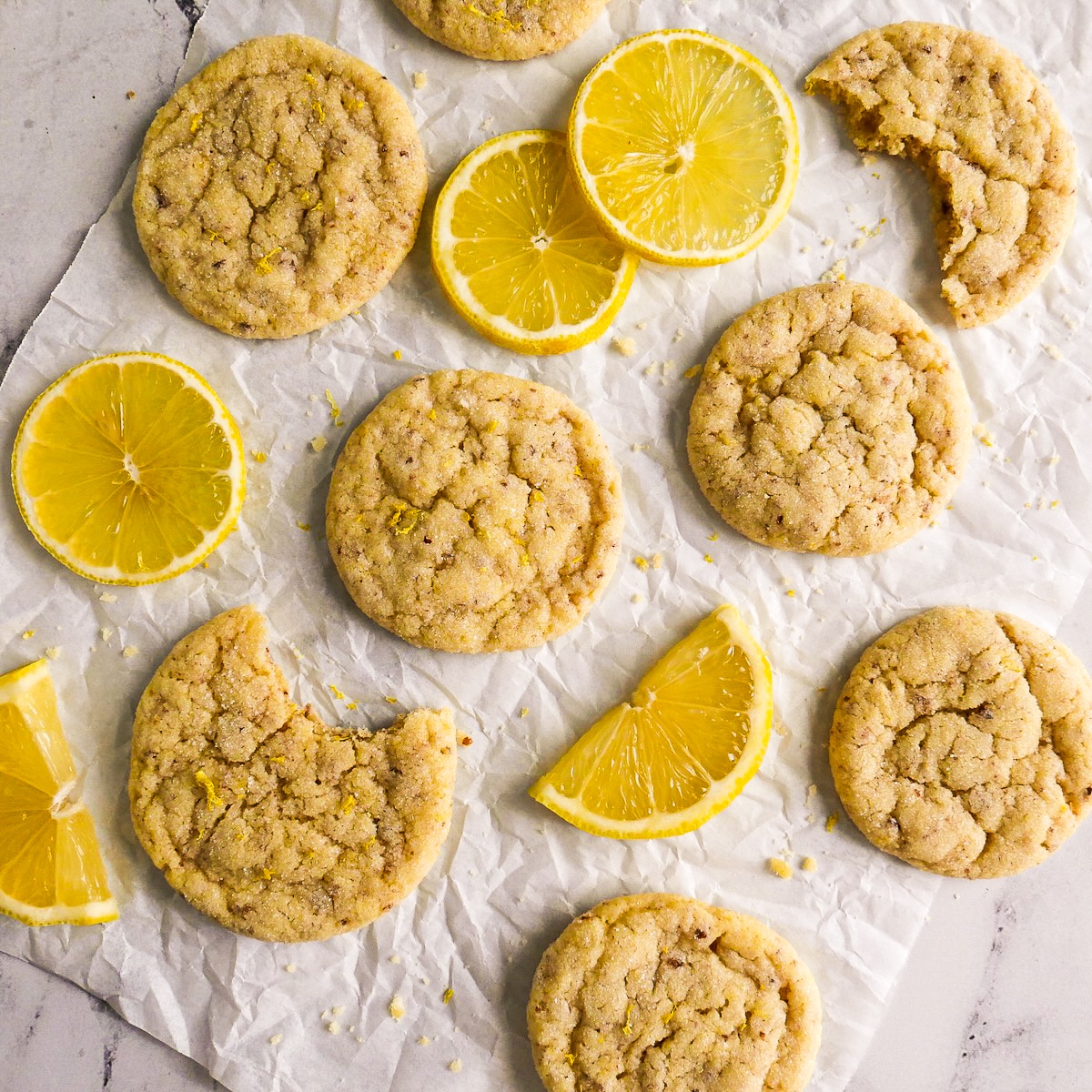 Crisp dairy free lemon cookies arranged on parchment.