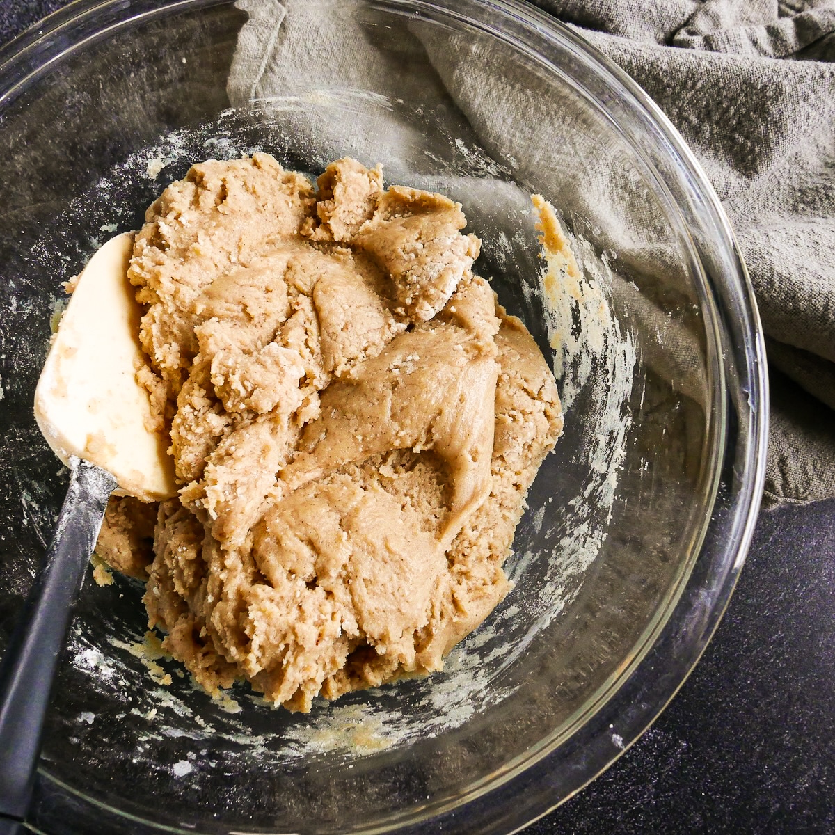 Snickerdoodle cookie dough in a mixing bowl with rubber spatula.