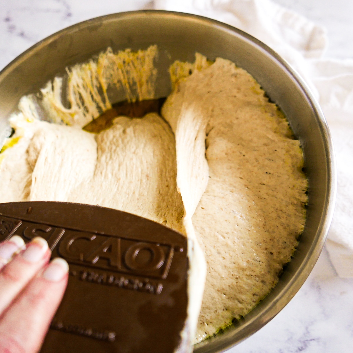 focaccia dough being folded over with a pastry scraper.