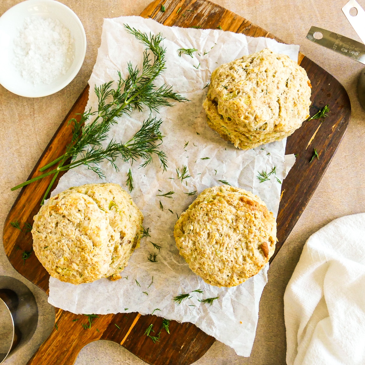 three biscuits on a cutting board with open biscuit on a white plate. 