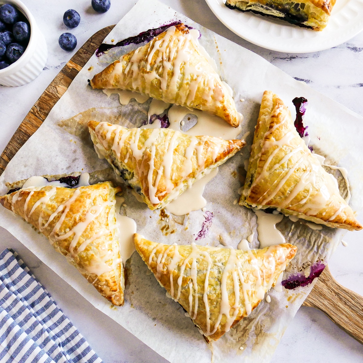 Glazed puff pastry turnovers arranged on parchment paper.