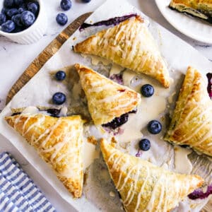 Easy blueberry turnovers arranged on parchment paper with one torn open.