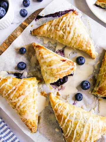 Easy blueberry turnovers arranged on parchment paper with one torn open.