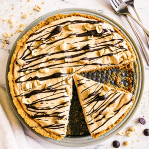 Creamy peanut butter pie with one slice cut and garnished with peanuts.