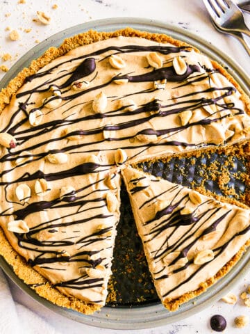 Creamy peanut butter pie with one slice cut and garnished with peanuts.