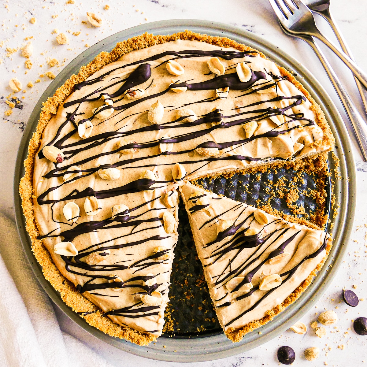 Creamy peanut butter pie with one slice cut and garnished with peanuts.