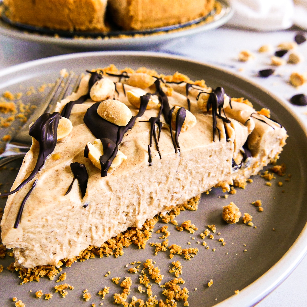 Slice of plant based peanut butter pie on a gray plate with crumbs.