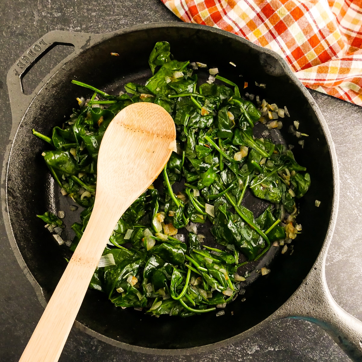 Cooking spinach with shallots and garlic in a pan.