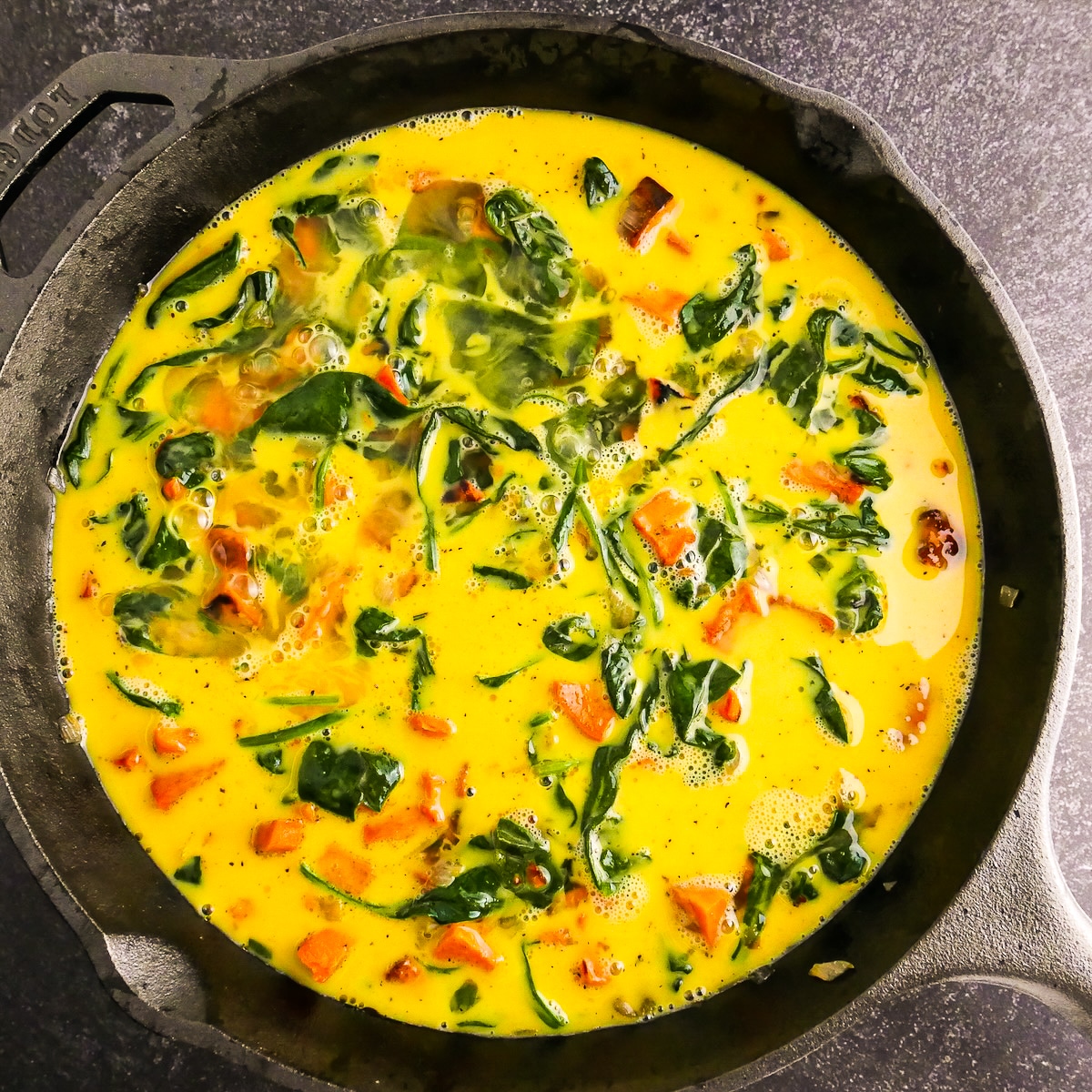 Whisked egg mixture poured into cooked veggie mixture in skillet.