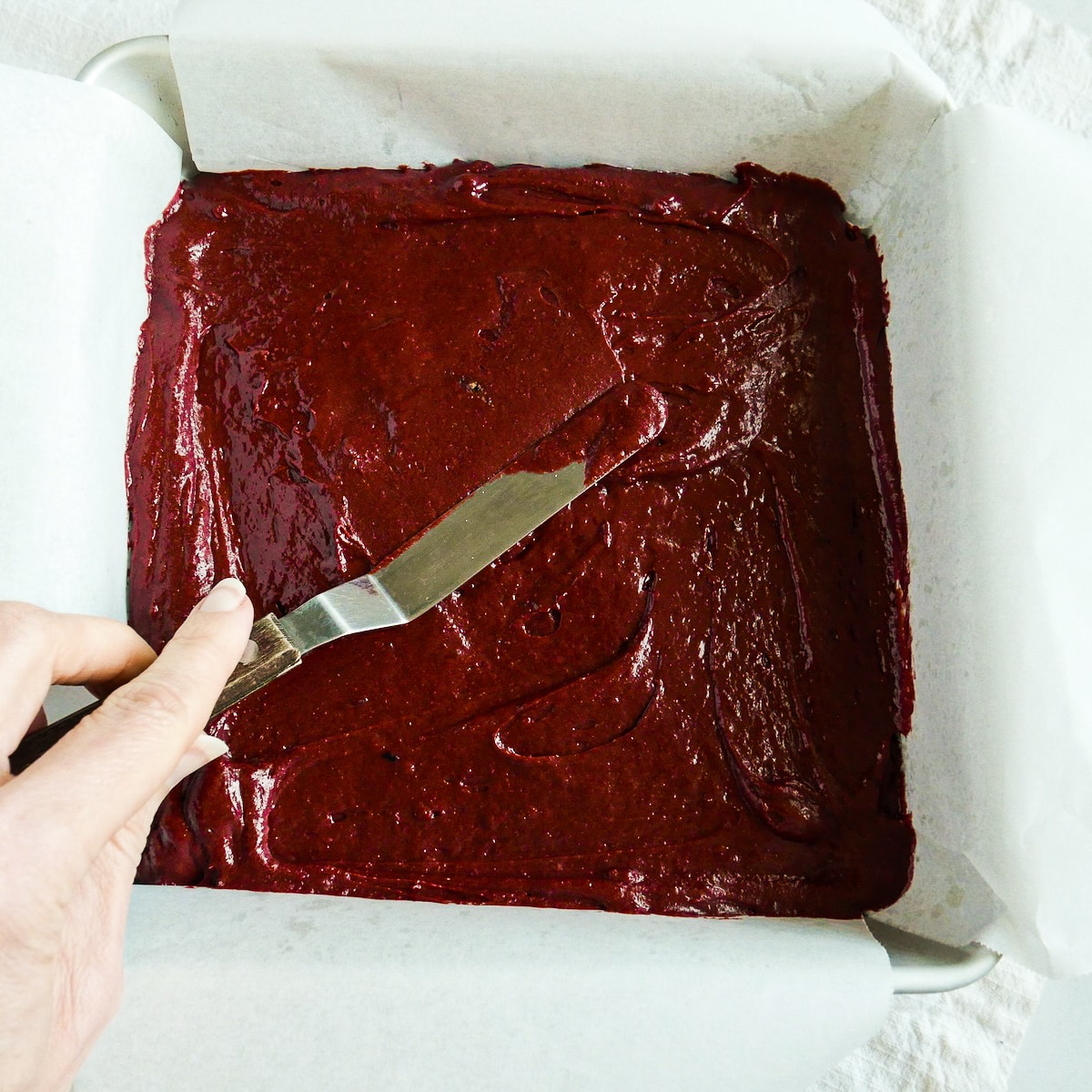 Spreading brownie batter into a prepared pan.