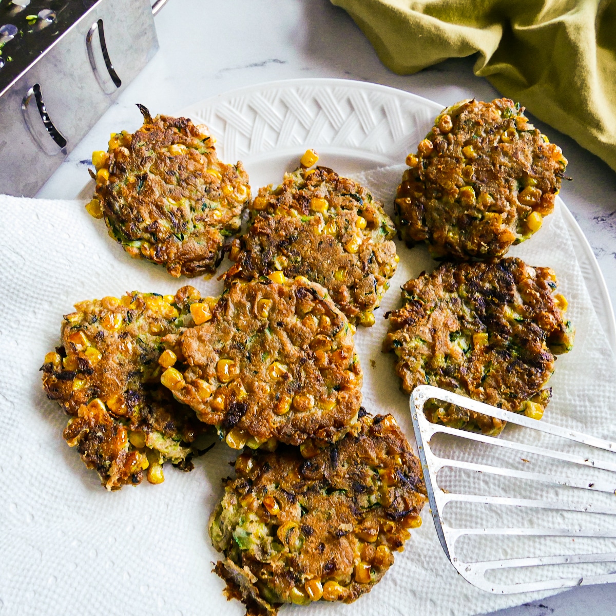 Crispy fritters placed on a paper towel-lined plate.