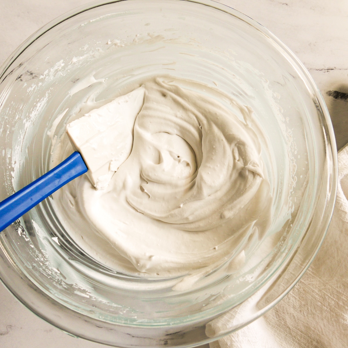 Bowl of coconut whipped cream with a rubber spatula.