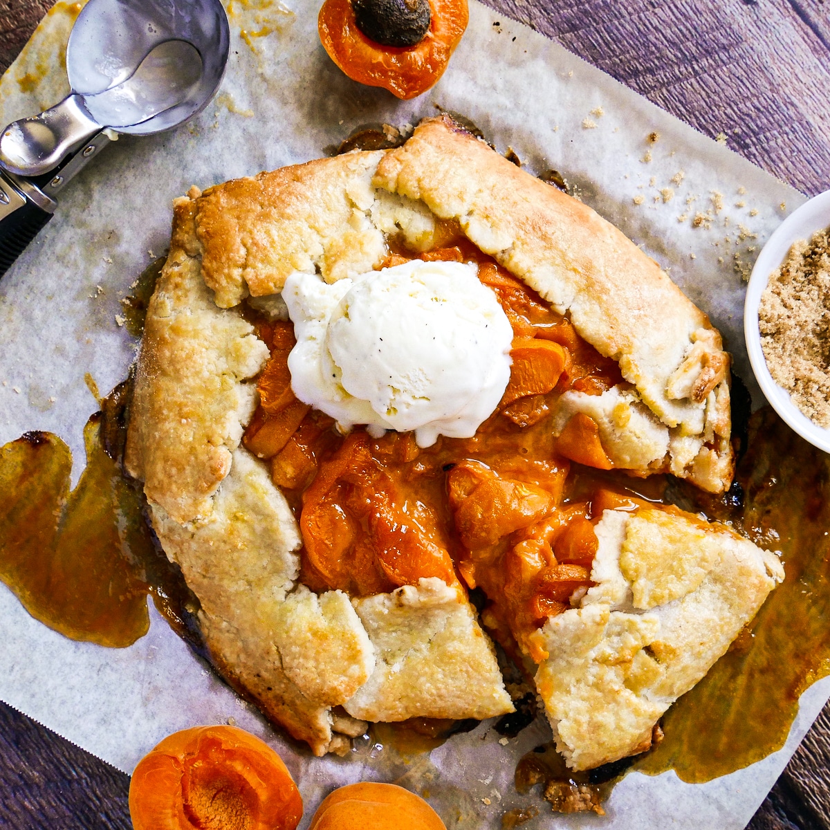 sliced-apricot-galette.jpg Sliced apricot galette on a baking sheet topped with a scoop of vanilla ice cream.