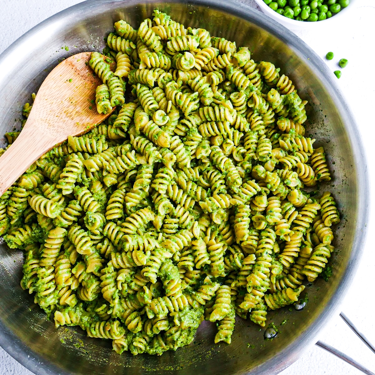 Cooked pasta combined with creamy pesto in a large pan.