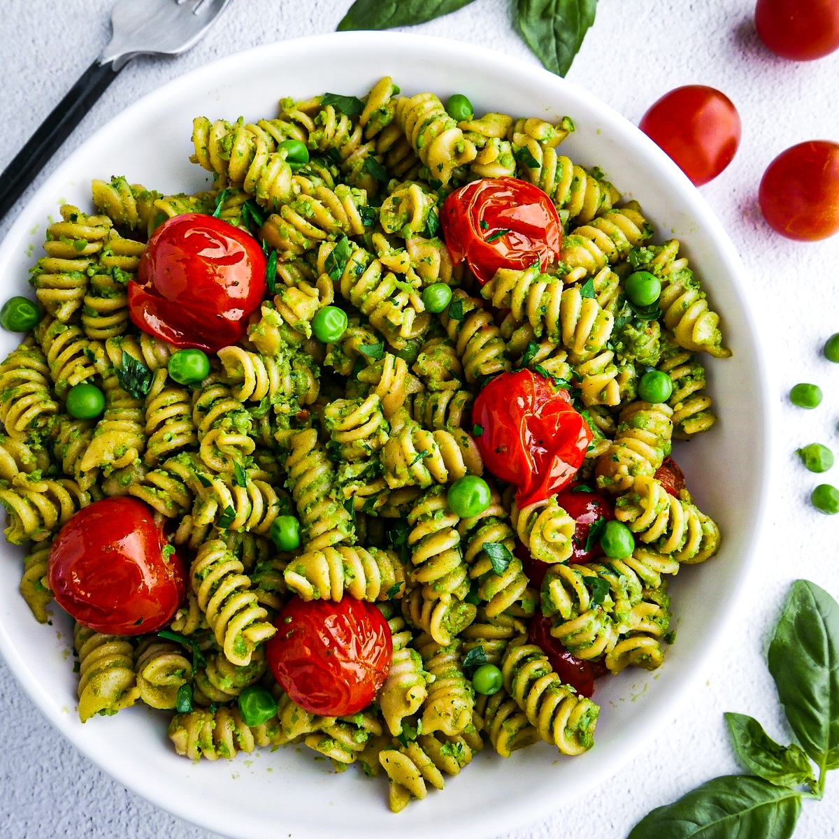 Large bowl of savory pesto pasta with fresh basil.