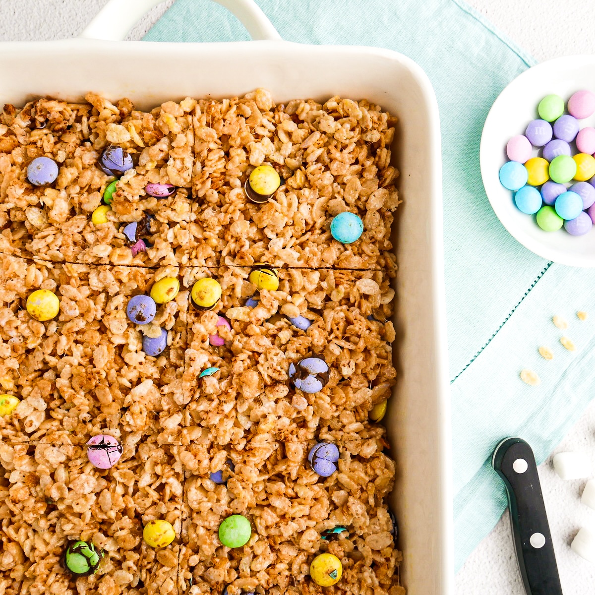 Sliced rice krispie bars in a baking pan with m&m's.