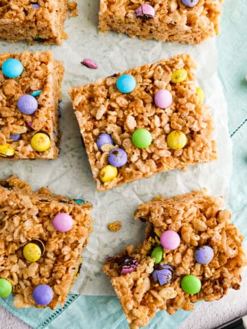 Soft and chewy rice krispie treats with m&m's arranged on parchment.