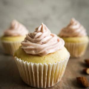 almond cupcakes arranged on a table with toasted almonds.