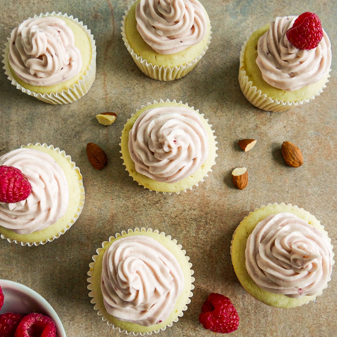 Cupcakes garnished with fresh raspberries arranged on a table.