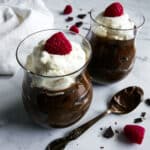 Two cups with vegan chocolate avocado mousse and topped with whipped cream.