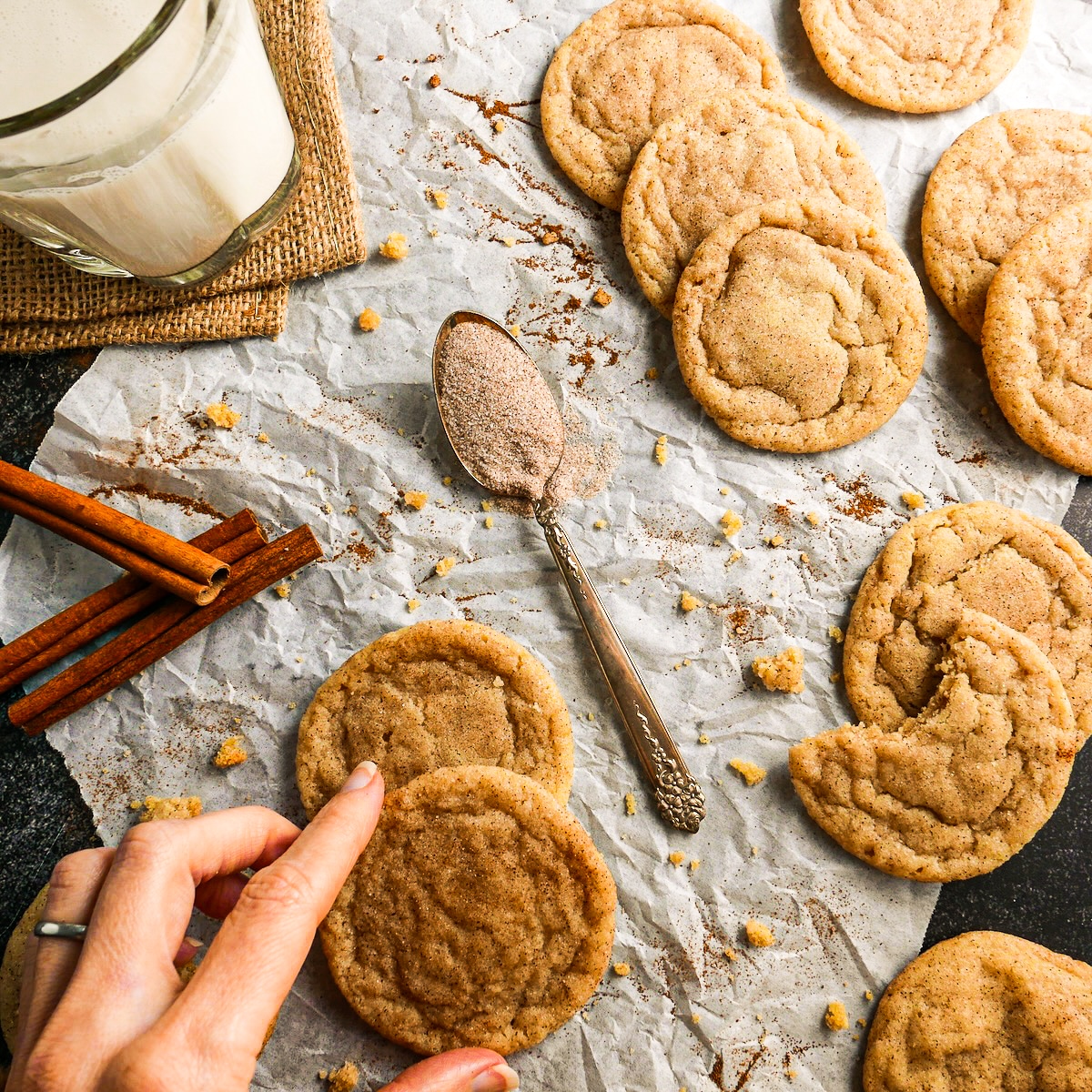 Hand reaching for a chewy snickerdoodle cookie.