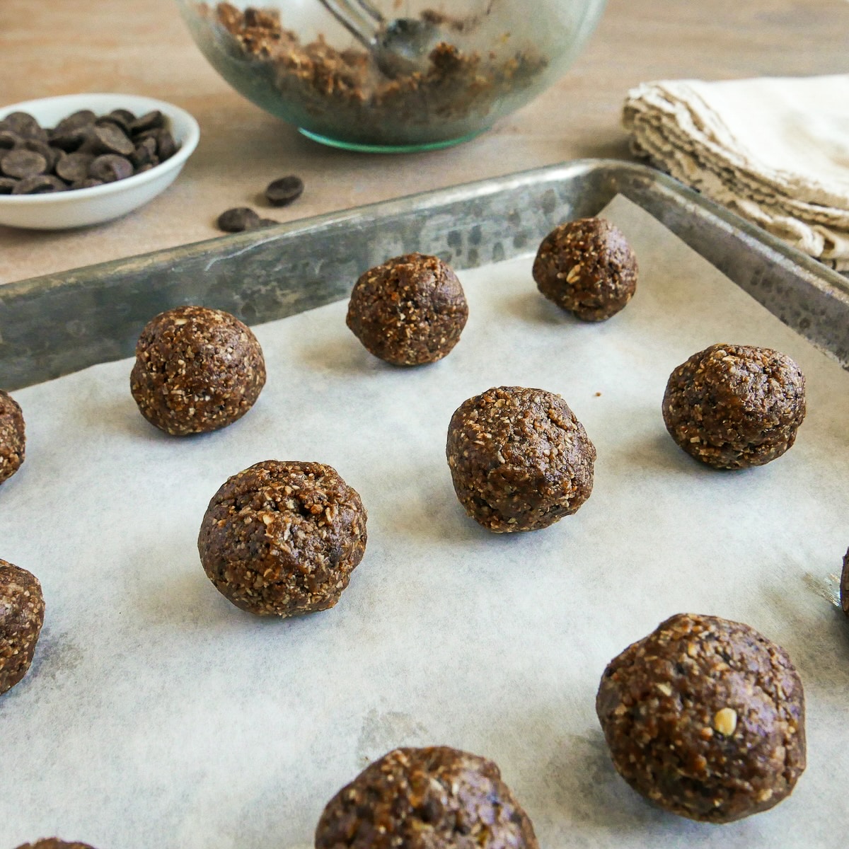 Rolled balls arranged on a parchment-lined baking sheet.