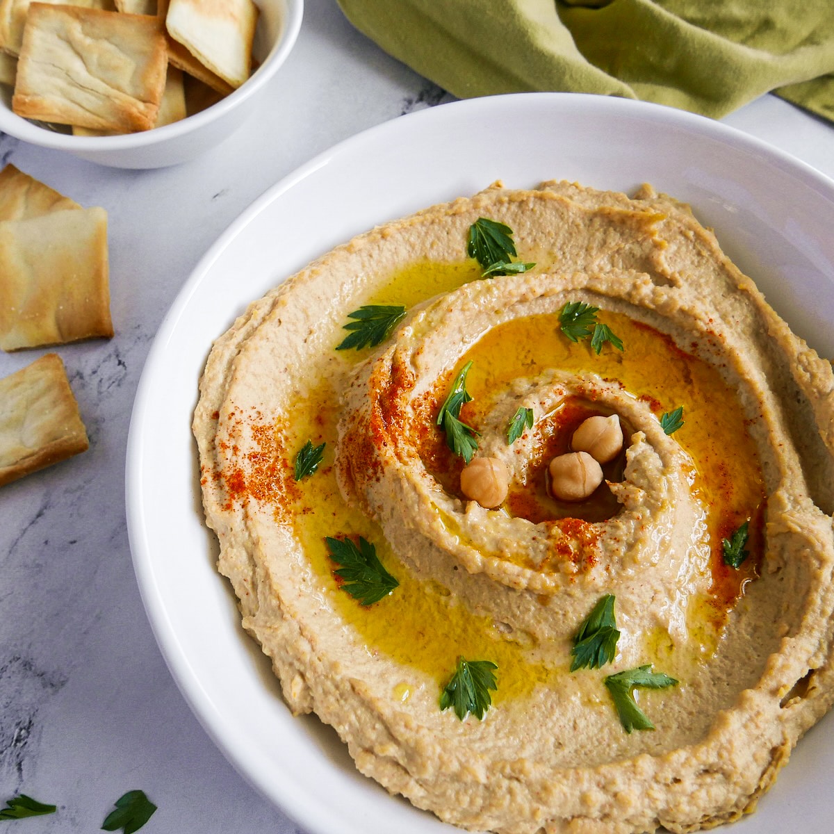 Creamy paprika hummus served in a bowl with fresh parsley.