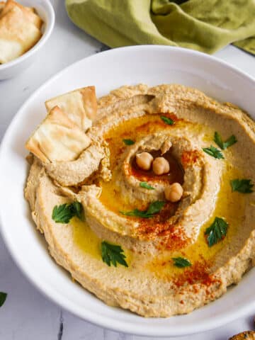 Smoky hummus garnished with parsley and olive oil.