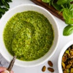 Creamy pistachio pesto in a bowl with a spoon.