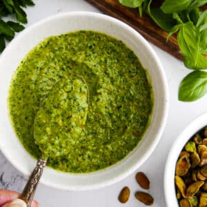 Creamy pistachio pesto in a bowl with a spoon.