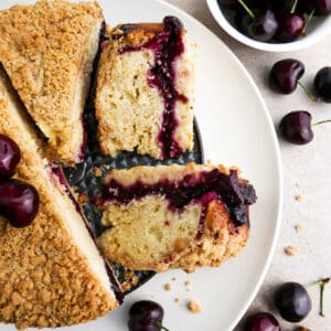 Sliced cherry coffee cake on a large platter with fresh cherries.