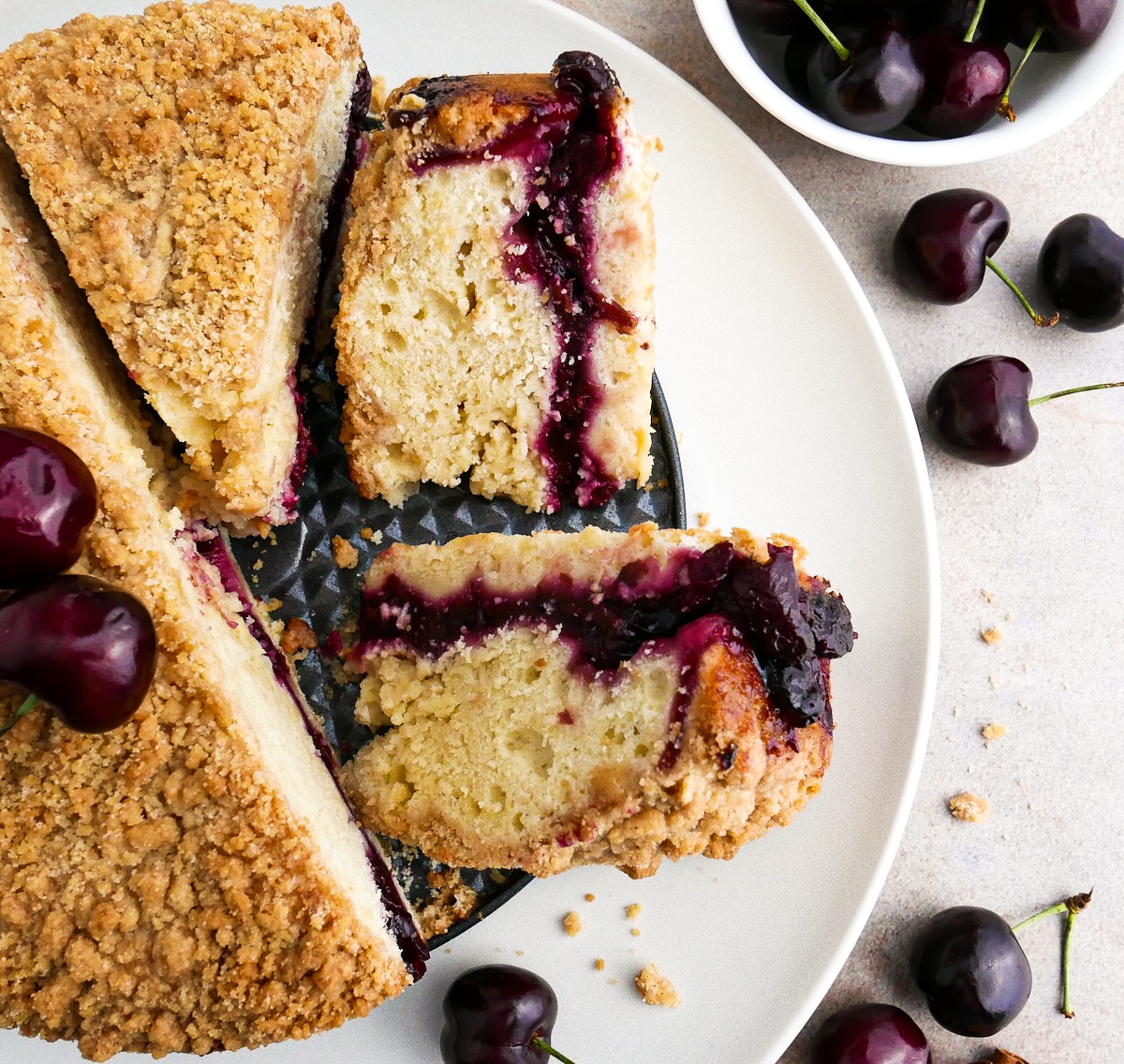 Sliced cherry coffee cake on a large platter with fresh cherries.