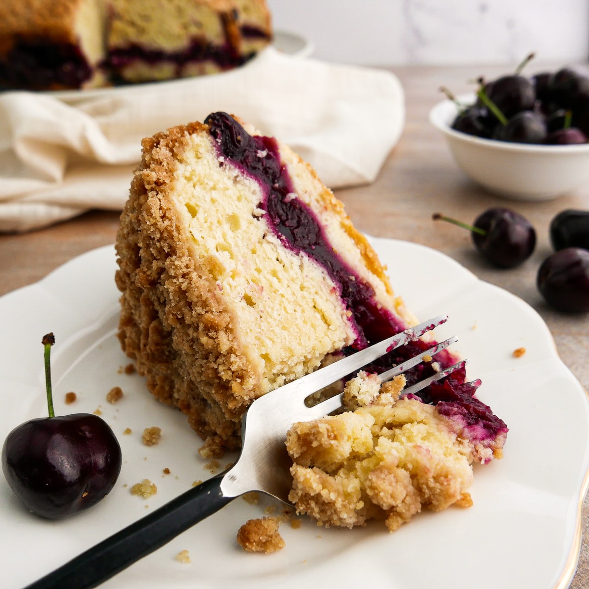 Slice of moist coffee cake with cherry filling resting on a plate.