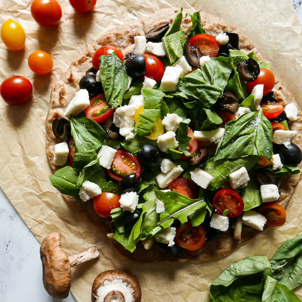 Assembled flatbread pizza on parchment paper. 