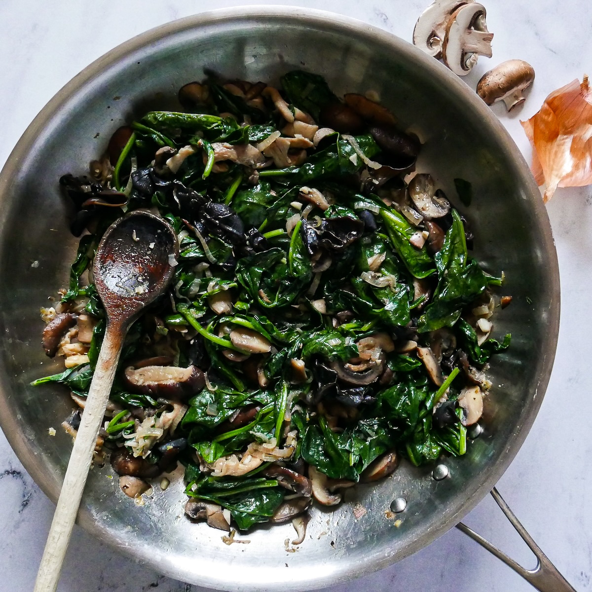 White wine and wilted spinach added to skillet.