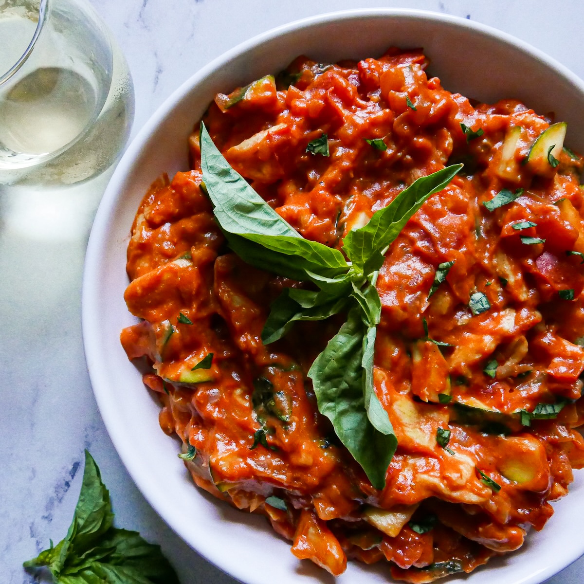 Creamy bowl of pasta garnished with fresh basil.